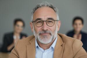 Close up mature man in business setting with two colleagues in background. photo