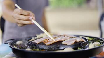 Hands of women using chopsticks to hold pork grilled. video