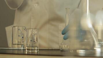 Laboratory technician in gloves and protective clothing working with pipette and chemical utensils in laboratory. video