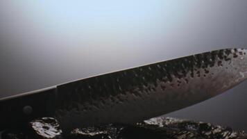 un costoso exclusivo cuchillo con un prima diseño en nubes de fumar entre el piedras despacio gira en frente de el cámara. video