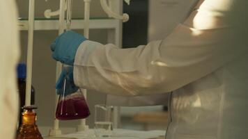 Hands of laboratory technician in protective clothing working with glassware in laboratory. video