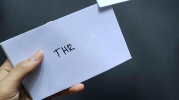 A woman straightens a white envelope labeled THR or Hari Raya Allowance. This allowance is usually given to employees before the Eid al-Fitr. video