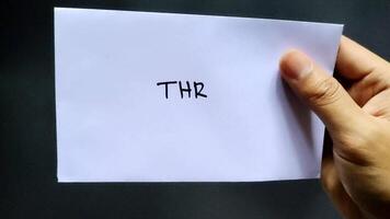 Man holding a white envelope labeled THR on a black paper background. video