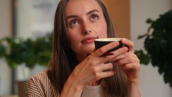 Pensive dreaming thinking create planning Caucasian woman female girl drinking tea coffee in cafe table writing notes in notebook copybook write ideas schedule to do list working lunch in cafeteria video