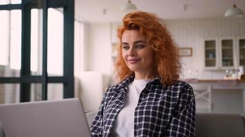 Caucasian calm smiling girl female woman using laptop computer online shopping at home in living room working distant e-learning with device addict typing chatting choosing internet purchase at couch video