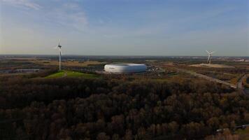 Aerial view of the Froettmaninger Hill with a wind turbine and a scenic view of the Allianz Arena in Munich. Freimann wind power plant and Munich football arena captured from above. video