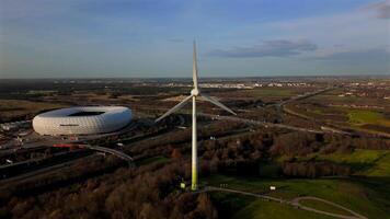 Aerial view of Froettmaninger Mullberg with wind turbine and a clear view of the Allianz Arena in Munich. Bird-eye perspective of the Freimann wind turbine and Munich football arena. video