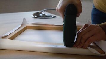 Canvas stretching. Hands staple canvas onto stretcher bars using powered stapler video