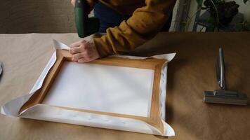 Process of stretching canvas onto stretcher bars using staple gun in workshop. video