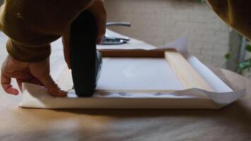 Hands stretching canvas on stretcher bars using staple gun in workshop. Gallery wrap. Print on canvas. video
