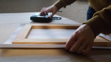 Process of stretching canvas on wooden stretcher frame in studio. video