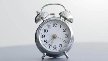 A stylish alarm clock rests on a bedside table in a serene bedroom. Its shiny metallic finish reflects light, creating a warm and inviting atmosphere perfect for relaxation and rest. video