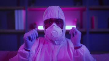 An African American man in a protective suit works online, surrounded by neon lights that create a futuristic atmosphere. He is focused and ready to take action in a modern setting. video