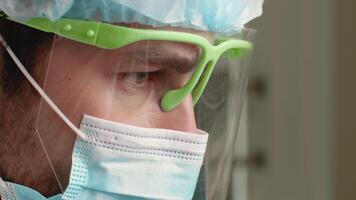 A dentist wearing protective gear carefully examines a patient in a modern dental clinic. The atmosphere reflects a commitment to health and safety during a consultation. video