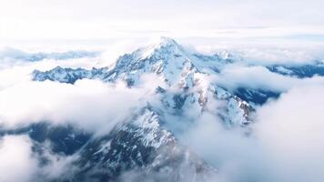 Drone flight over majestic snow-capped mountains peeking through swirling cloudscape video