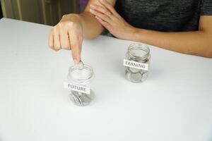 A person is putting coins in a jar with a label on it photo