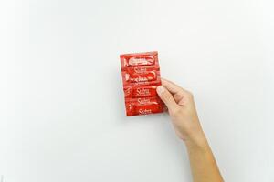 A person holding a red condom packet photo