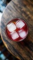 A glass of red drink with ice cubes on top photo