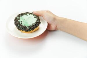 A hand holding a small cupcake with green frosting photo