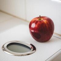 An apple sits on top of a digital scale photo