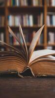 An open book on a table in front of a library of books photo