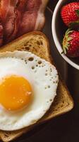 A plate with an egg, bacon and strawberries photo