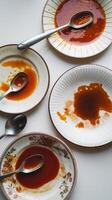 A table with four plates with sauce and spoons photo