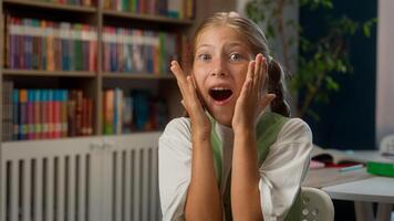 Overjoyed shocked surprised Caucasian little girl child kid schoolgirl schoolchild pupil student learner looking at camera screaming yelling wow shouting shock surprise indoor school library education photo