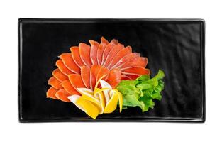 slicing appetizer of red fish slices on black plate on a white background top view photo
