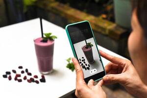 A woman taking picture of mulberry smoothie for advertisement photo
