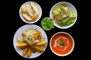 Lunch set made of tomato cream soup salad chicken with potato, lemonade on black background photo