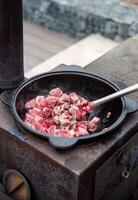 man frying pork and beef meat in a cauldron in the backyard photo