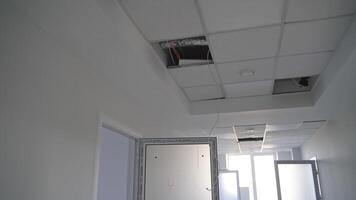 White corridor in a newly-built building. Focus on the unfinished pieces of ceiling cover. Open doors lock close up. video