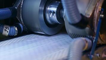 Conveyor line with special material for nappies manufacturing. Rotating rollers over the line of conveyor. Close up. video