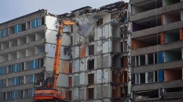 Powerful excavator tears off the pieces of destroyed house and throws them down. Demolition of a large building ruined by an earthquake. video