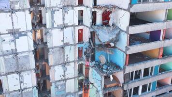 Demolishing machine breaks the walls and floors of the big ruined building. Aerial view of the deconstruction site. video