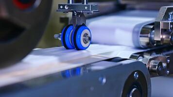 Process of making recesses on the inner surface of a diaper. Little blue roller spinning on a conveyor line. Close up. video