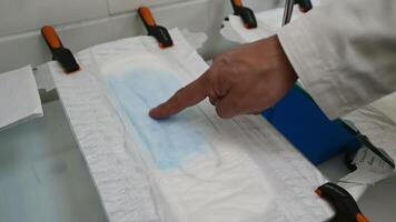 Researcher's hand checking the absorption of the inner layer in diaper with his finger. Male hand presses the napkin to the diaper and show that it's dry. Close up. video