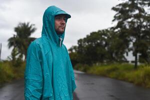 Depressive concept with lonely man in a raincoat standing on wet road under rain close up photo