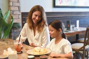 Little girl and mother hugging and looking at each other in a cafe photo