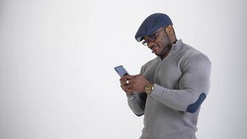 Man with phone in studio. African man using phone isolated on grey studio background video