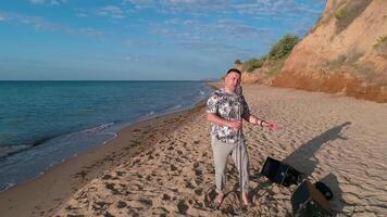 Man singing into microphone outdoor. Young man singing into microphone while standing on the beach video
