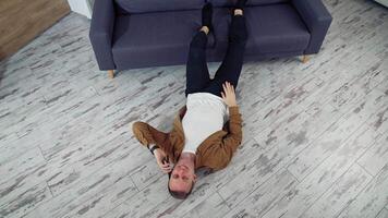 Man relaxing using mobile phone. Happy young man talking on mobile phone and lying on the floor video
