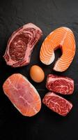 Various protein sources concept rib eye salmon steak pork egg top view on a black stone background photo