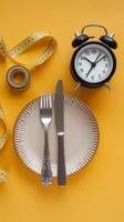 An empty plate with a fork, knife and measuring tape on a yellow background photo