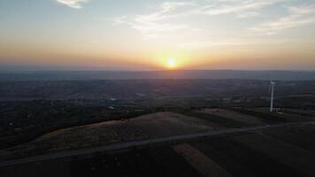 Car Road with the wind farm on the crest of a hill filmed with a drone at sunset. video