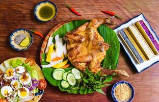 Grilled chicken in vietnamese style with colorful rice in bamboo and boiled eggs on wooden table photo