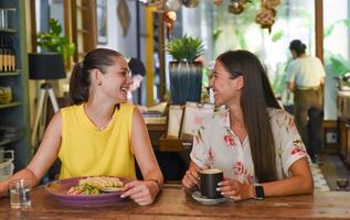 Two best friends talking, laughing and eating in a cafe photo