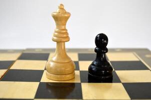 Two chess pieces of queen and pawn against each other on the background of the chessboard photo