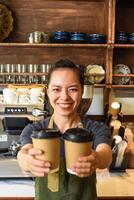 Vietnamese smiling waitress holds paper cups with coffee in a cafe photo